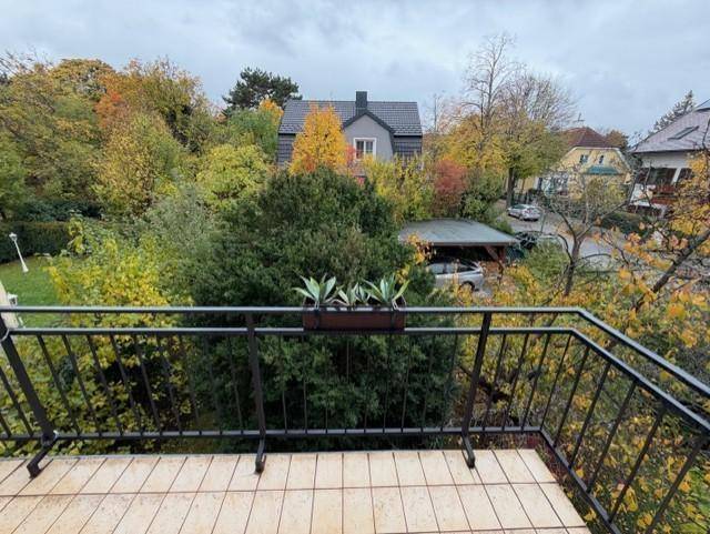 Balkon mit Fliesenboden und Blick auf die herbstliche Landschaft, mit Pflanzen dekoriert.