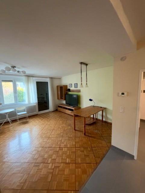 Geräumiger Wohnbereich mit Parkettboden, TV-Möbeln und viel Tageslicht, offen und einladend.