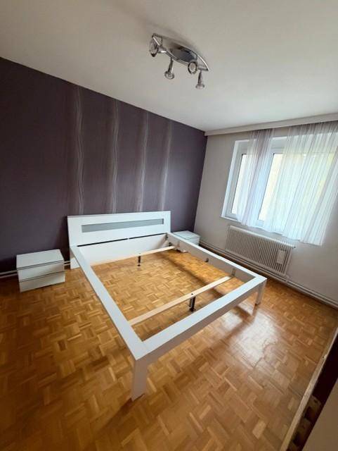 Helles Schlafzimmer mit Parkettboden und Fenster, ideal für ein Doppelbett, mit Nachttischen.