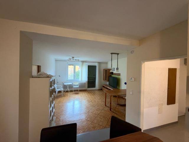 Heller Wohn- und Essbereich mit Parkettboden und Zugang zum Balkon, offen gestaltet.