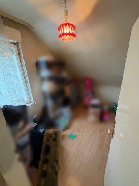 Unscharfer Innenraum mit schrägen Wänden, Parkettboden und einem Fenster.