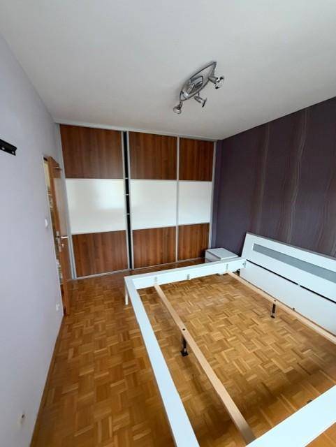 Schlafzimmer mit Parkettboden und Einbauschrank, bereit zur Einrichtung, mit dunkler Akzentwand.