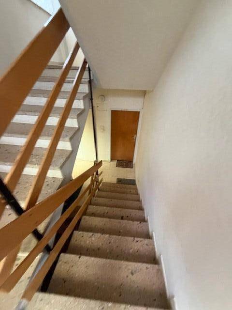 Treppenhaus mit Holzgeländer und Zugang zu den Wohnbereichen, hell und funktional.