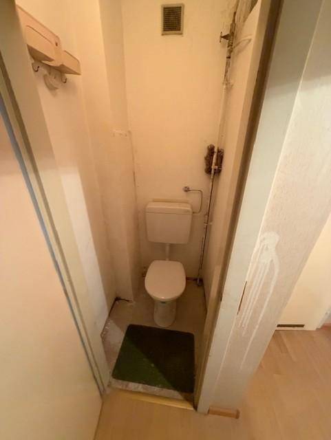 Kleines WC mit Toilette und Lüftungsgitter, einfach und funktional.