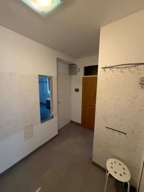 Eingangsbereich mit Fliesenboden und Garderobe, funktional und hell, mit Spiegel.