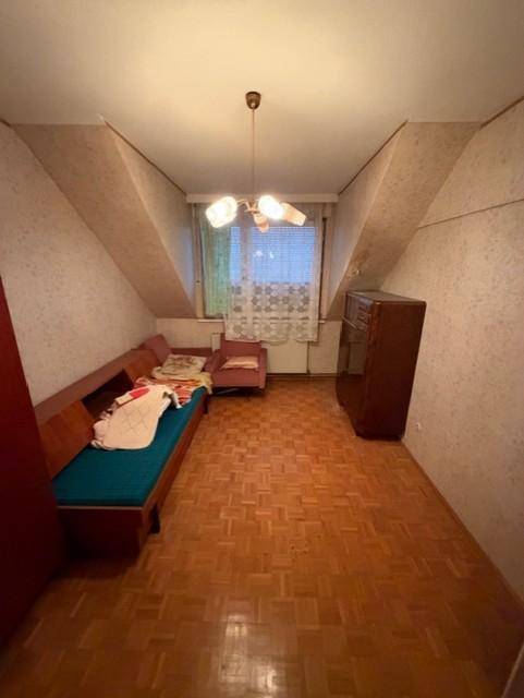 Gemütliches Dachzimmer mit Parkettboden, schrägen Wänden und einfacher Einrichtung.