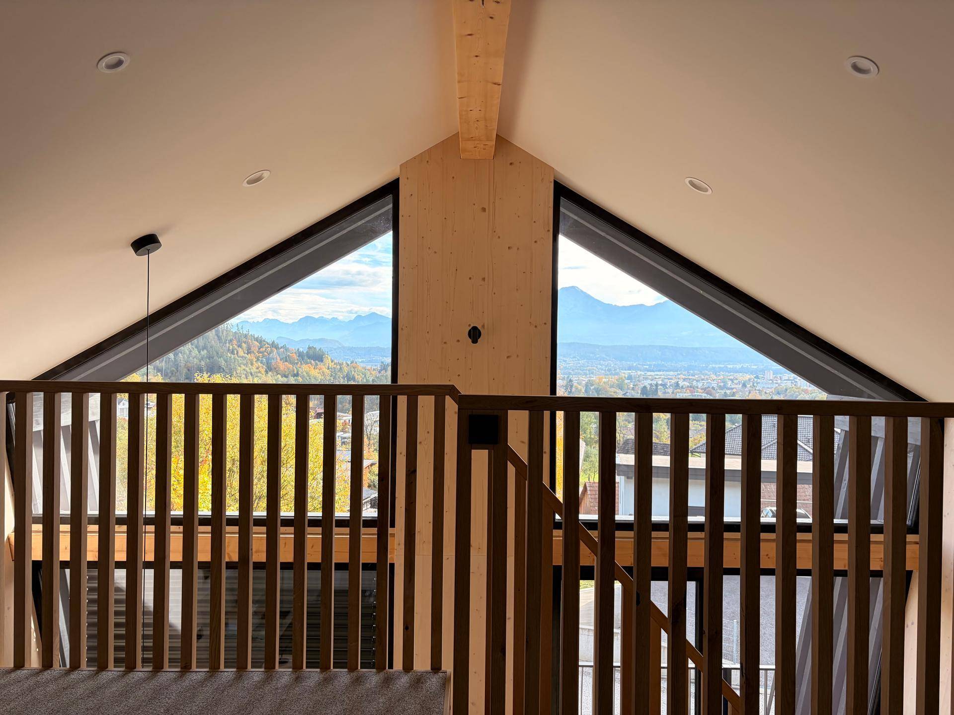 Heller Innenraum mit Holzvertäfelung und großen Giebelfenstern, die einen weiten Blick bieten.
