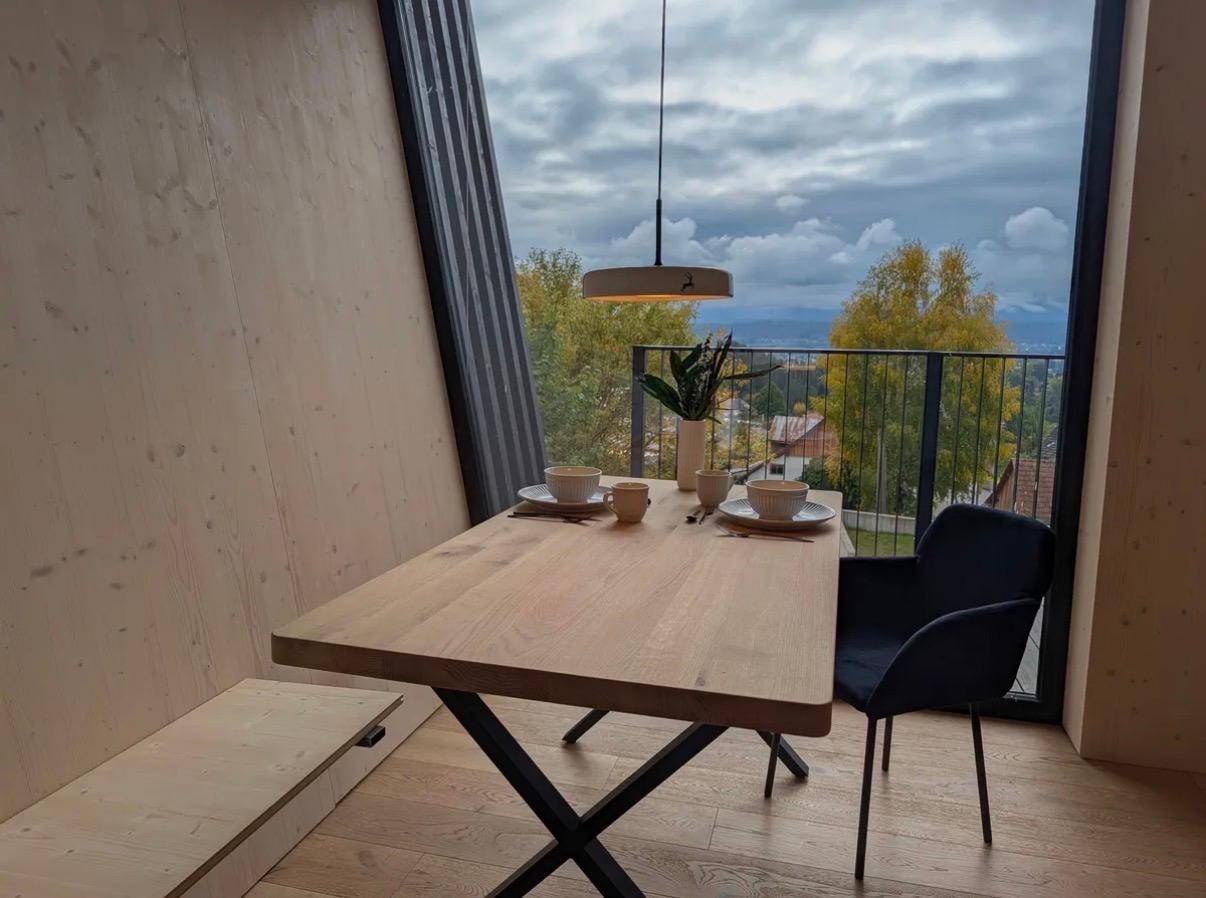 Gemütlicher Essbereich mit Holztisch, moderner Pendelleuchte und Zugang zu einem Balkon.
