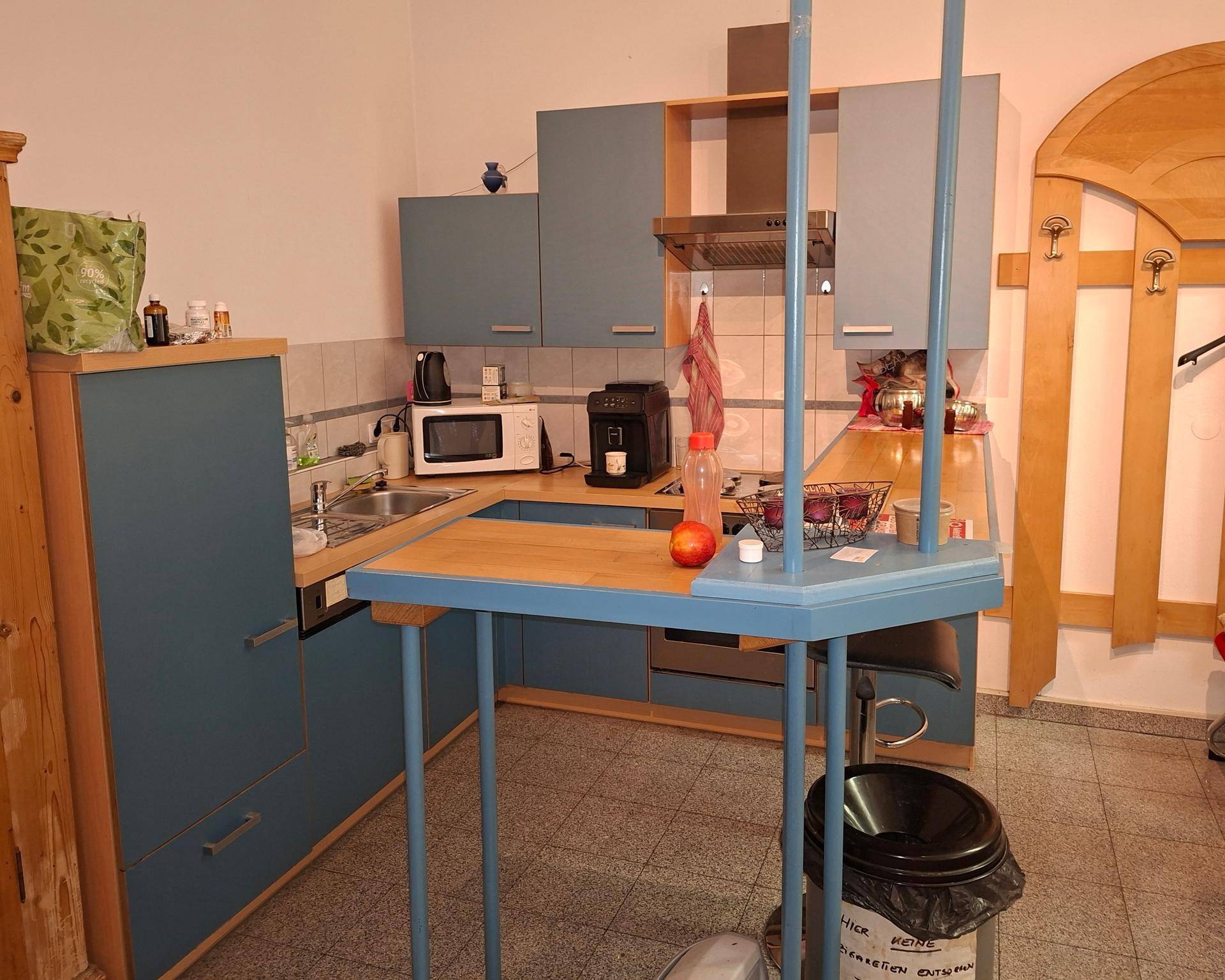 Kleine Küche mit blauen Einbauschränken, Holzarbeitsplatten und integrierten Geräten.