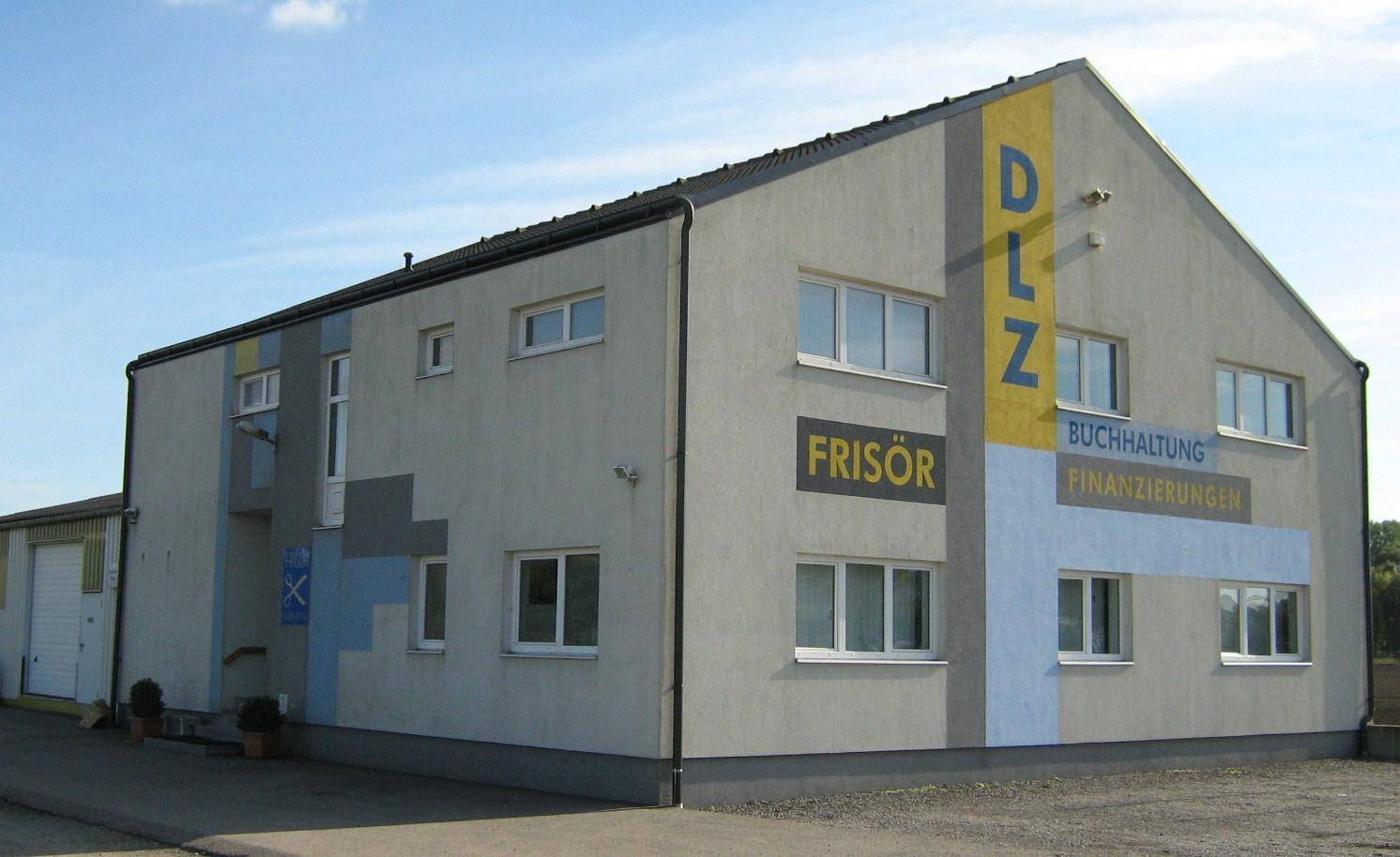 Modernes Geschäftsgebäude mit grauer Fassade, großen Fenstern und Werbeschildern für verschiedene Unternehmen.
