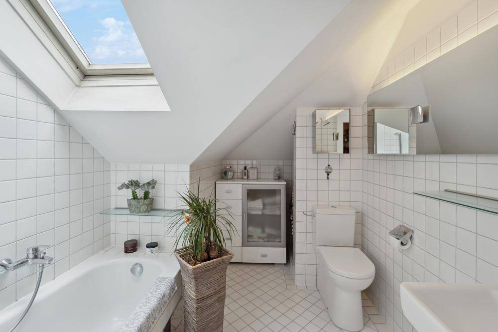 Helles Badezimmer mit Dachflächenfenster, Badewanne und WC