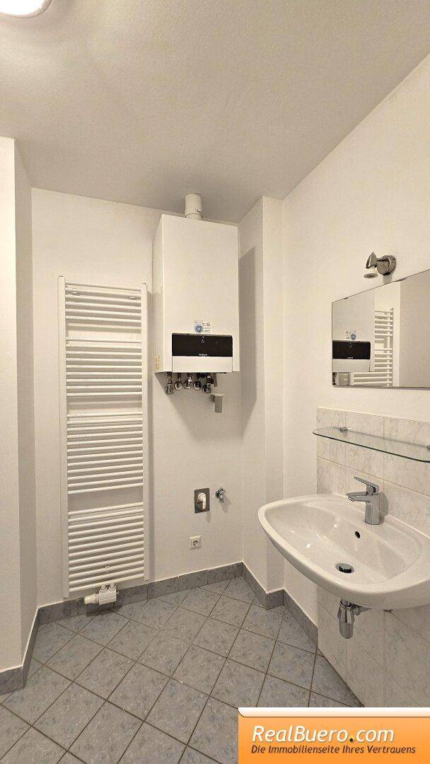 Badezimmer mit Wanne, Handwaschbecken, Handtuchtrockner, Waschmaschinenanschluss