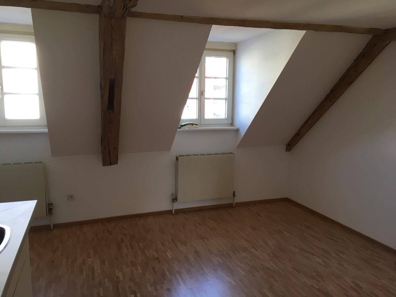 Dachboden mit Dachschräge, leerer Raum mit Holzboden und Fenster nach draußen