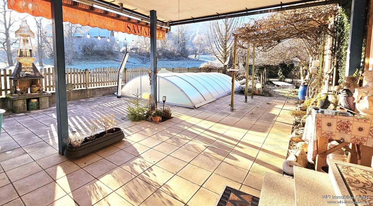 Überdachte Terrasse mit Pool und Gartenblick